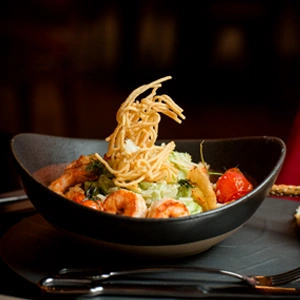 Side view shrimp caesar plate topped with potato shoestrings